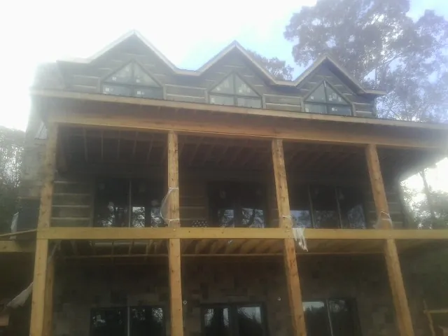 Dormers and porch framing on a large log home under construction — Roof Coating work by our crew in Spencer