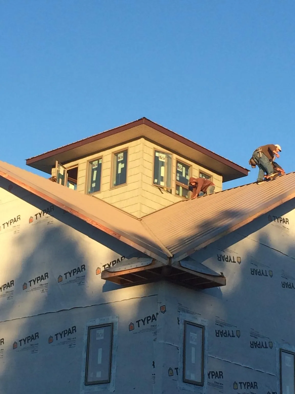 Roofers working around a rooftop cupola on a new metal roof at sunset — Roof Waterproofing in Spencer by Roofing Brothers